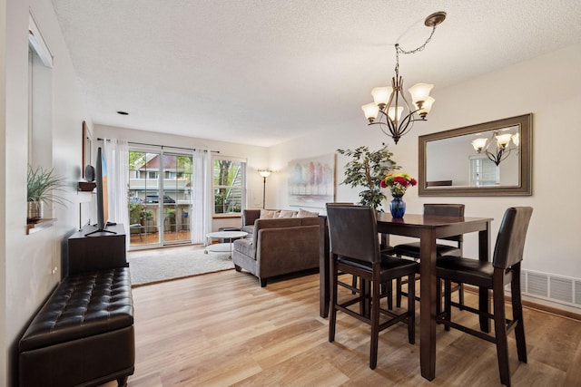 1925 Shenandoah Ct Unit G, Plymouth, MN 55447 - dining space featuring a chandelier, light wood-style flooring, and a textured ceiling