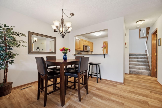 1925 Shenandoah Ct Unit G, Plymouth, MN 55447 - dining space featuring light wood-style flooring, stairs, a chandelier, baseboards, and a textured ceiling