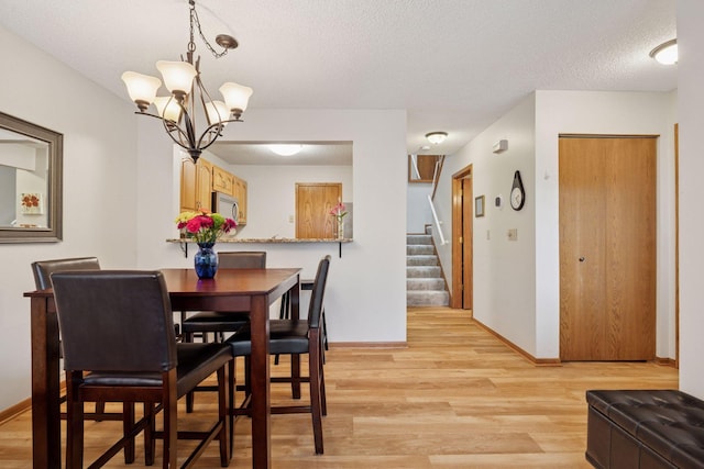 1925 Shenandoah Ct Unit G, Plymouth, MN 55447 - dining space featuring light wood-style floors, stairs, a textured ceiling, baseboards, and a chandelier