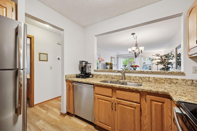 1925 Shenandoah Ct Unit G, Plymouth, MN 55447 - kitchen featuring appliances with stainless steel finishes, a sink, light wood-type flooring, light stone counters, and a chandelier