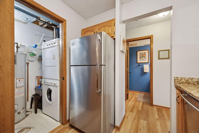 1925 Shenandoah Ct Unit G, Plymouth, MN 55447 - kitchen featuring freestanding refrigerator, stacked washer / dryer, water heater, light wood-style flooring, and a textured ceiling