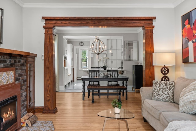 3812 Elliot Ave, Minneapolis, MN 55407 - living room with a brick fireplace, light wood-type flooring, baseboards, ornamental molding, and a chandelier