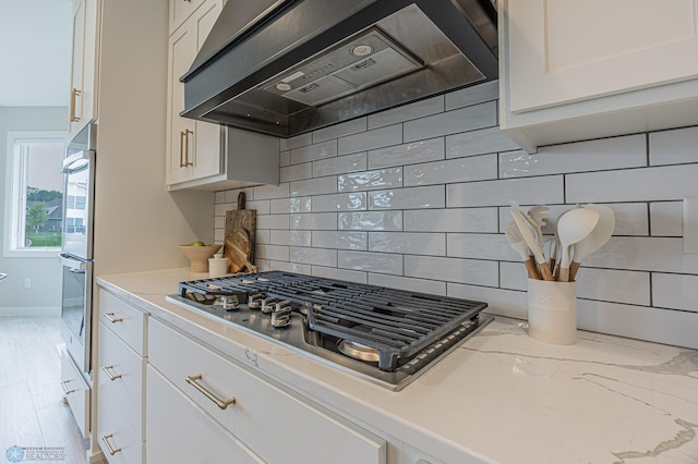3340 2nd St E, West Fargo, ND 58078 - kitchen featuring ventilation hood, appliances with stainless steel finishes, white cabinets, and decorative backsplash