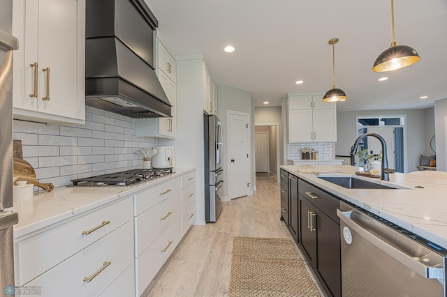 3340 2nd St E, West Fargo, ND 58078 - kitchen with stainless steel appliances, a sink, custom range hood, light wood-style flooring, and white cabinetry