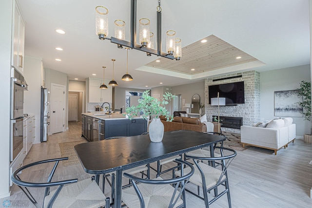 3340 2nd St E, West Fargo, ND 58078 - dining area with a raised ceiling, recessed lighting, a large fireplace, light wood-style flooring, and a chandelier