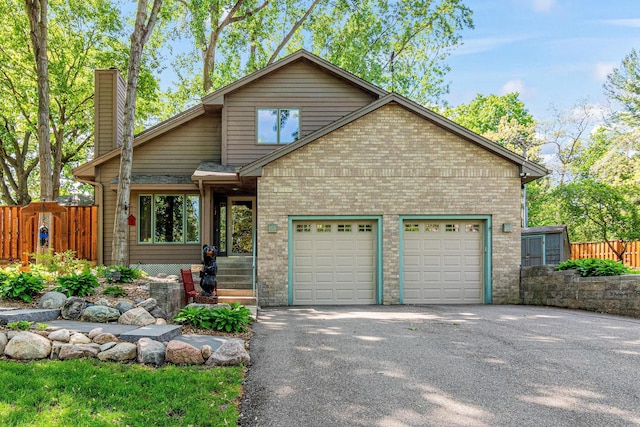 2195 Bayview Pl, Orono, MN 55391 - view of front of home featuring asphalt driveway, an attached garage, brick siding, and a chimney