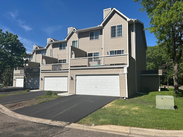 10946 Johnson St NE, Blaine, MN 55434 - view of front of house with a chimney, a balcony, a garage, and asphalt driveway