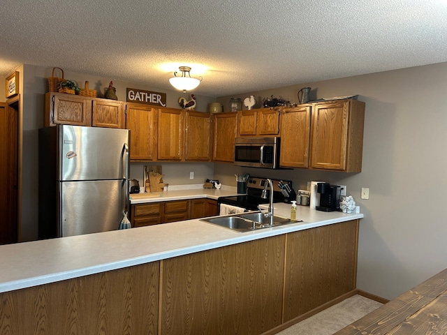 10946 Johnson St NE, Blaine, MN 55434 - kitchen featuring appliances with stainless steel finishes, brown cabinets, a sink, a peninsula, and a textured ceiling