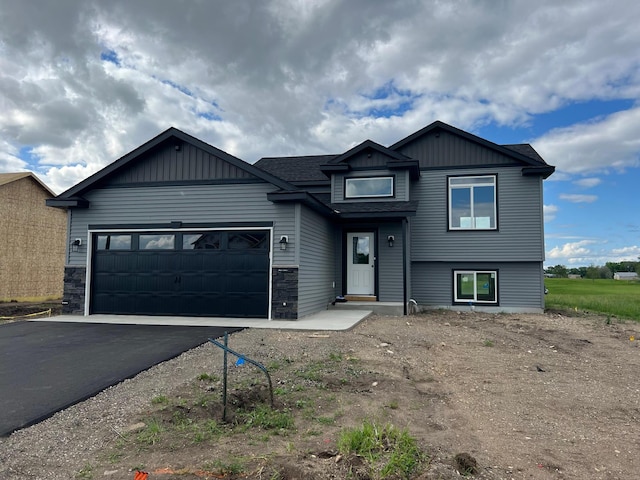 240 9th St SW, Rice, MN 56367 - view of front of home with driveway, an attached garage, stone siding, and board and batten siding