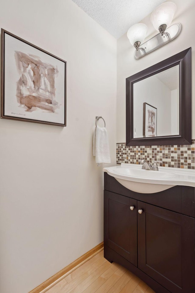 2658 133rd St W, Rosemount, MN 55068 - bathroom featuring tasteful backsplash, vanity, wood finished floors, a textured ceiling, and baseboards