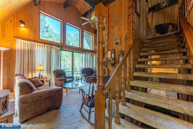 3240 Breezy Point Rd, Tower, MN 55790 - carpeted living area with wood walls, high vaulted ceiling, ceiling fan, stairway, and beamed ceiling