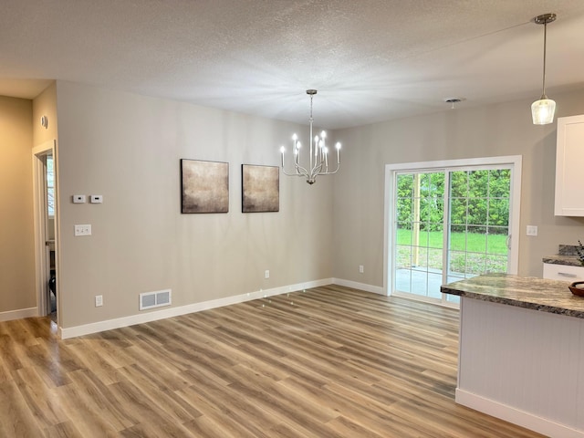 105 7th St, Hoffman, MN 56339 - unfurnished dining area featuring light wood finished floors, baseboards, a chandelier, and a textured ceiling