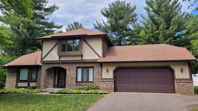 669 Lake Pine Dr, Shoreview, MN 55126 - tudor house featuring asphalt driveway, brick siding, an attached garage, a shingled roof, and a front yard