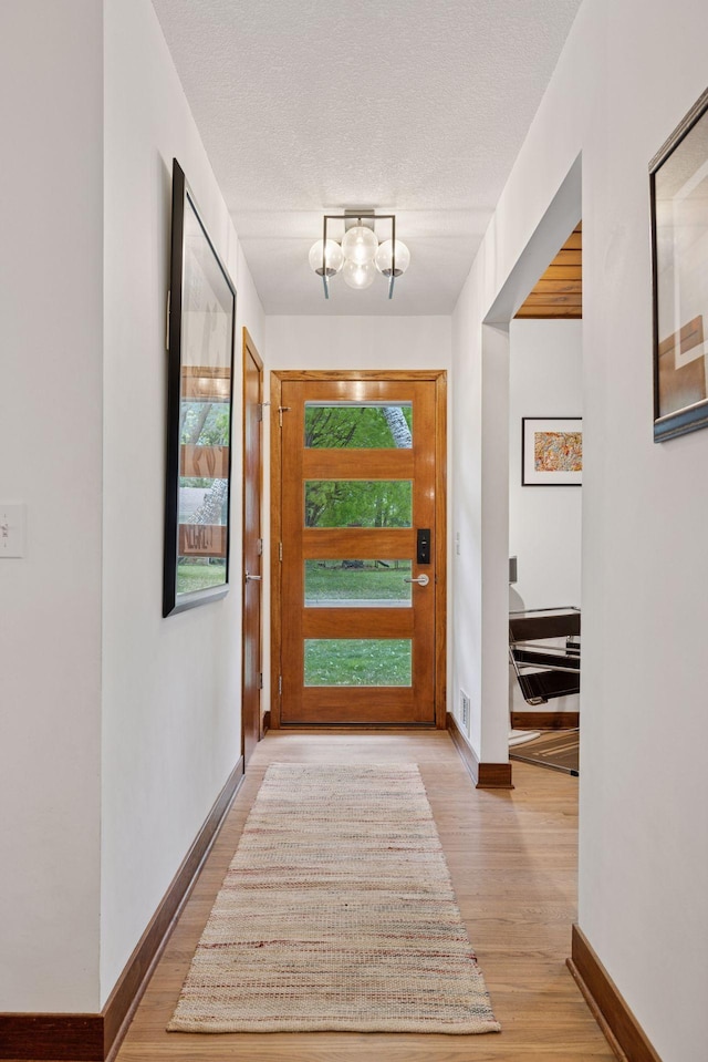 18201 Kathleene Dr, Minnetonka, MN 55345 - entrance foyer with a chandelier, wood finished floors, baseboards, and a textured ceiling