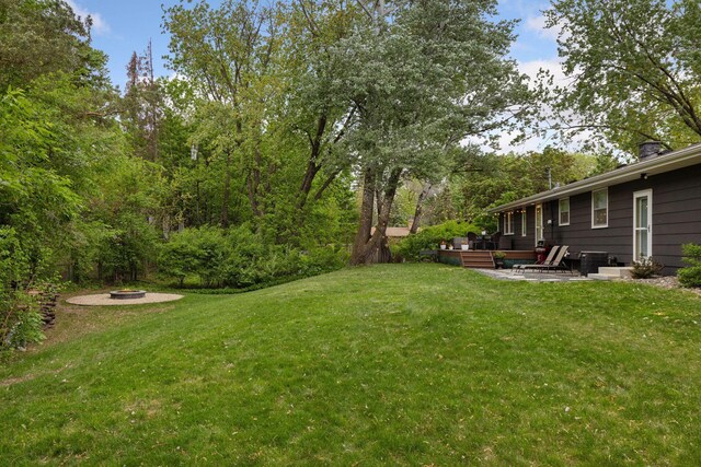18201 Kathleene Dr, Minnetonka, MN 55345 - view of grassy yard featuring a fire pit, a wooden deck, and a patio