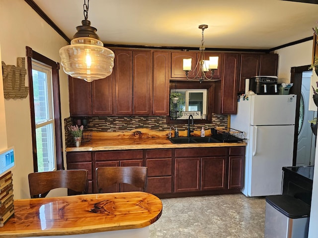 205 2nd Ave W, Lamberton, MN 56152 - kitchen with a sink, freestanding refrigerator, decorative backsplash, a chandelier, and decorative light fixtures