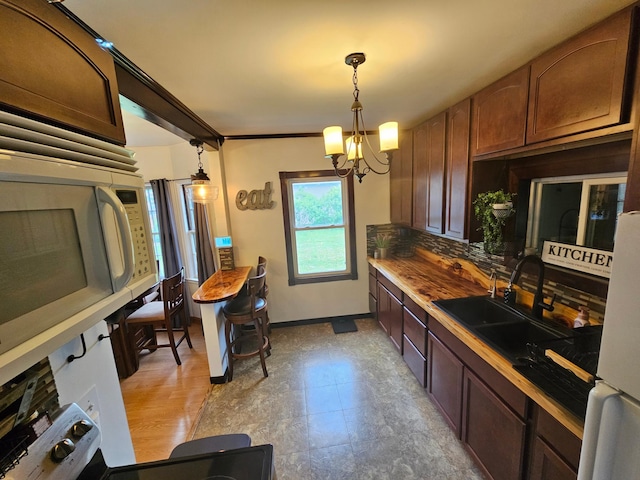 205 2nd Ave W, Lamberton, MN 56152 - kitchen featuring a chandelier, a sink, white appliances, and pendant lighting