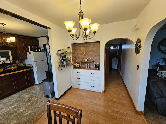 205 2nd Ave W, Lamberton, MN 56152 - kitchen featuring a chandelier, freestanding refrigerator, arched walkways, and dark brown cabinetry
