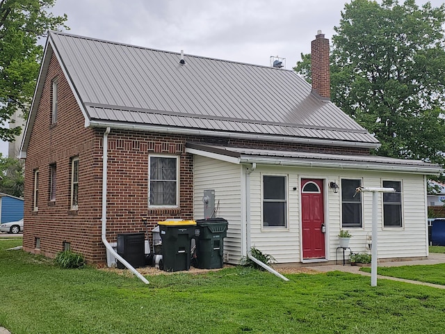 205 2nd Ave W, Lamberton, MN 56152 - back of house with a chimney, a lawn, brick siding, and metal roof