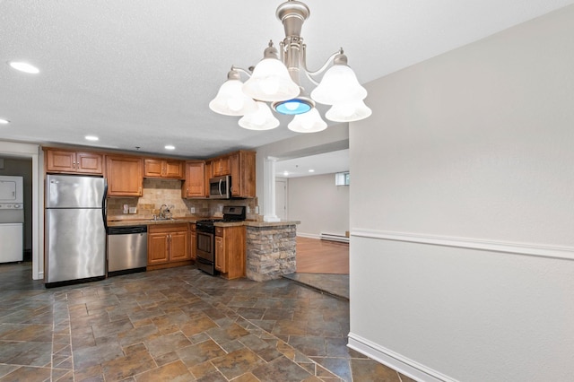 1930 Aldrich Ave S Unit C001, Minneapolis, MN 55403 - kitchen with stainless steel appliances, stacked washing machine and dryer, a chandelier, dark stone finish flooring, and baseboards