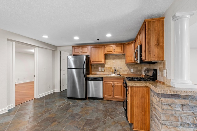 1930 Aldrich Ave S Unit C001, Minneapolis, MN 55403 - kitchen featuring appliances with stainless steel finishes, ornate columns, tasteful backsplash, a sink, and a textured ceiling