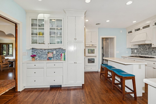 5319 Upton Ave S, Minneapolis, MN 55410 - kitchen featuring stainless steel gas cooktop, double oven, tasteful backsplash, light countertops, and a kitchen bar
