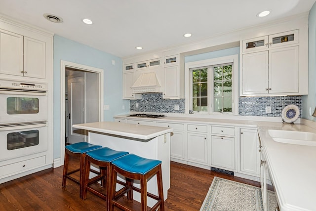 5319 Upton Ave S, Minneapolis, MN 55410 - kitchen with double oven, custom exhaust hood, stainless steel gas cooktop, a kitchen breakfast bar, and tasteful backsplash