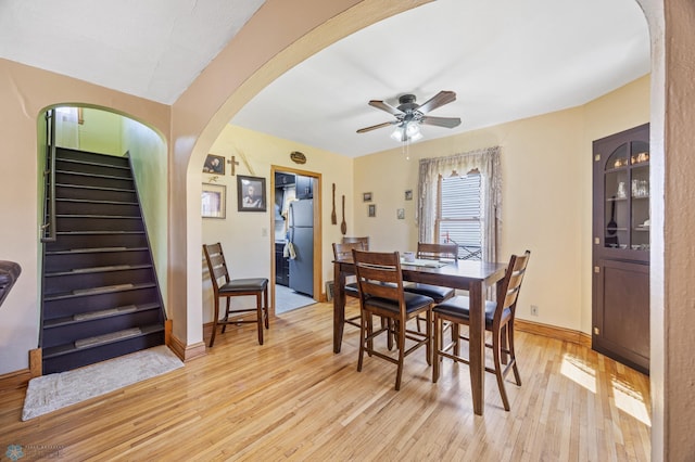 114 2nd Ave E, West Fargo, ND 58078 - dining space featuring light wood-style floors, a ceiling fan, stairs, arched walkways, and baseboards