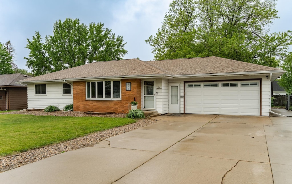 1000 17th St SW, Austin, MN 55912 - single story home featuring a garage, driveway, a front yard, brick siding, and a shingled roof
