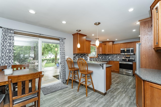 1000 17th St SW, Austin, MN 55912 - kitchen featuring appliances with stainless steel finishes, a peninsula, healthy amount of natural light, backsplash, and recessed lighting
