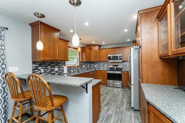 1000 17th St SW, Austin, MN 55912 - kitchen with stainless steel appliances, a peninsula, brown cabinetry, a breakfast bar area, and recessed lighting