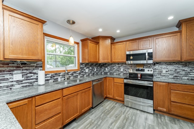 1000 17th St SW, Austin, MN 55912 - kitchen featuring stainless steel appliances, a sink, backsplash, brown cabinetry, and decorative light fixtures