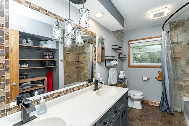 1000 17th St SW, Austin, MN 55912 - bathroom featuring double vanity, toilet, tiled shower / bath, baseboards, and stone finish flooring