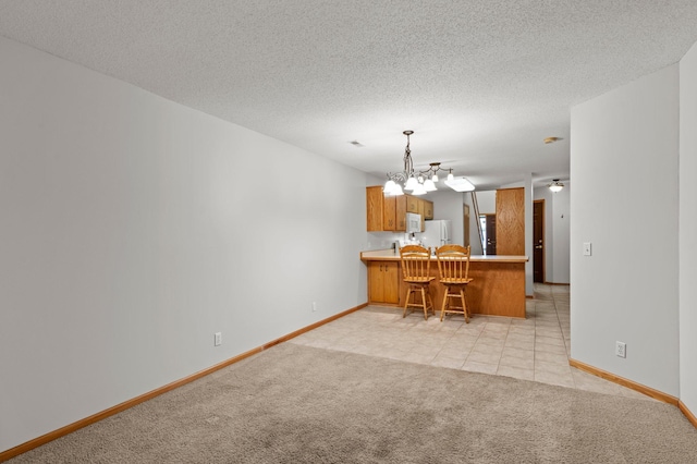 1022 17th Ave SE, Forest Lake, MN 55025 - kitchen featuring a peninsula, light carpet, a chandelier, brown cabinets, and white microwave