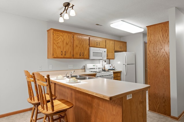 1022 17th Ave SE, Forest Lake, MN 55025 - kitchen featuring white appliances, a sink, light countertops, a peninsula, and brown cabinetry