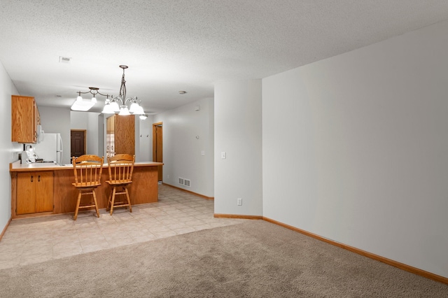 1022 17th Ave SE, Forest Lake, MN 55025 - kitchen featuring a peninsula, brown cabinets, freestanding refrigerator, baseboards, and light carpet