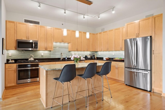 215 10th Ave S Unit 312, Minneapolis, MN 55415 - kitchen with stainless steel appliances, light brown cabinetry, a breakfast bar, and light wood-style floors