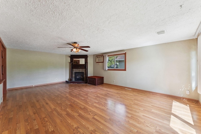 39 Magnolia Ave E, Saint Paul, MN 55117 - unfurnished living room with a textured ceiling, light wood-style flooring, a ceiling fan, a tiled fireplace, and a wall mounted air conditioner