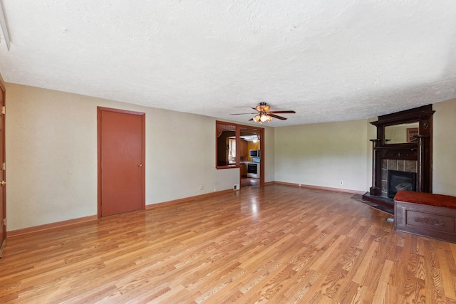 39 Magnolia Ave E, Saint Paul, MN 55117 - unfurnished living room with a ceiling fan, a fireplace, light wood-type flooring, a textured ceiling, and baseboards