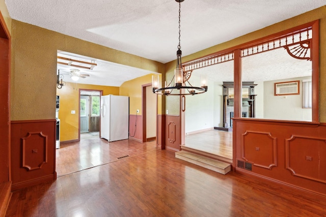 39 Magnolia Ave E, Saint Paul, MN 55117 - unfurnished dining area with a textured ceiling, wood finished floors, a chandelier, wainscoting, and a wall mounted air conditioner