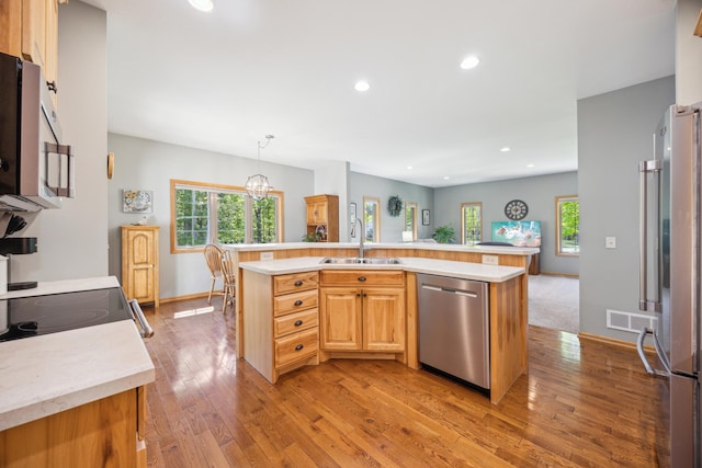 14450 Blackberry Ct, Baxter, MN 56425 - kitchen with stainless steel appliances, a sink, light wood finished floors, recessed lighting, and a kitchen island with sink