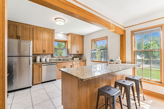 5640 13th Ave S, Minneapolis, MN 55417 - kitchen featuring appliances with stainless steel finishes, a breakfast bar area, backsplash, light stone counters, and light tile patterned flooring