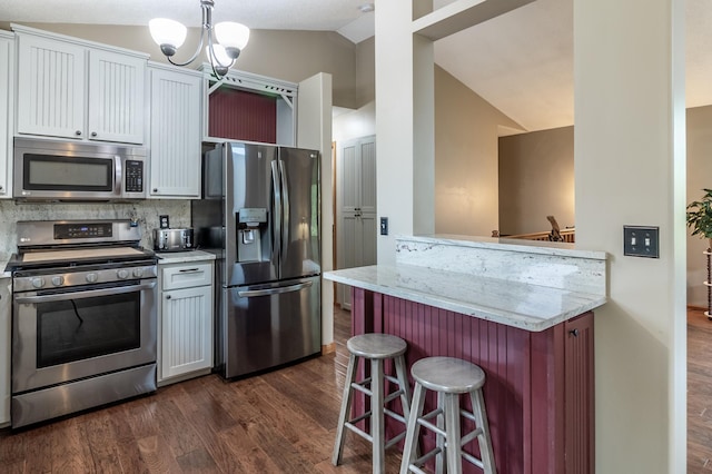 2053 45th St SE, Saint Cloud, MN 56304 - kitchen with stainless steel appliances, vaulted ceiling, dark wood-style flooring, a kitchen bar, and a chandelier