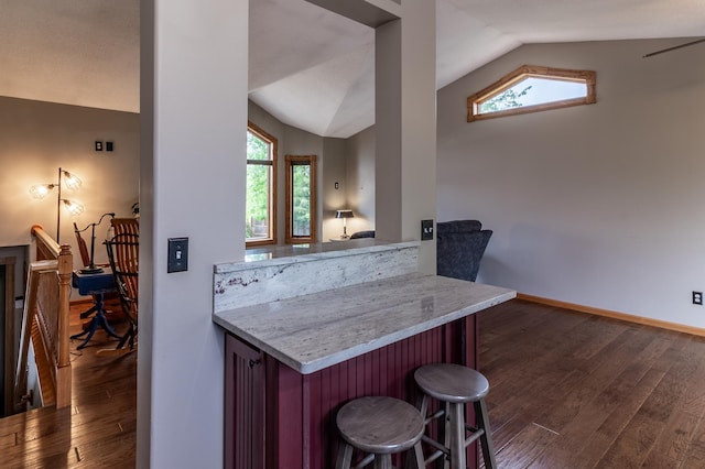 2053 45th St SE, Saint Cloud, MN 56304 - kitchen featuring lofted ceiling, dark wood finished floors, a kitchen bar, baseboards, and light stone counters