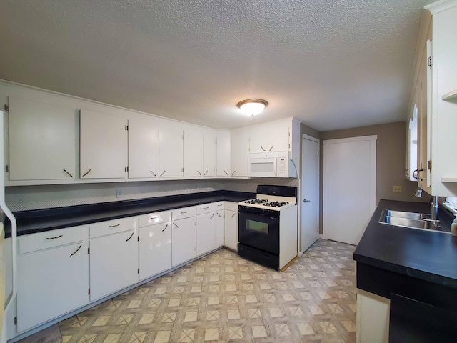 732 Vernon Ave NW, Elk River, MN 55330 - kitchen with range with gas cooktop, white microwave, a sink, dark countertops, and white cabinetry