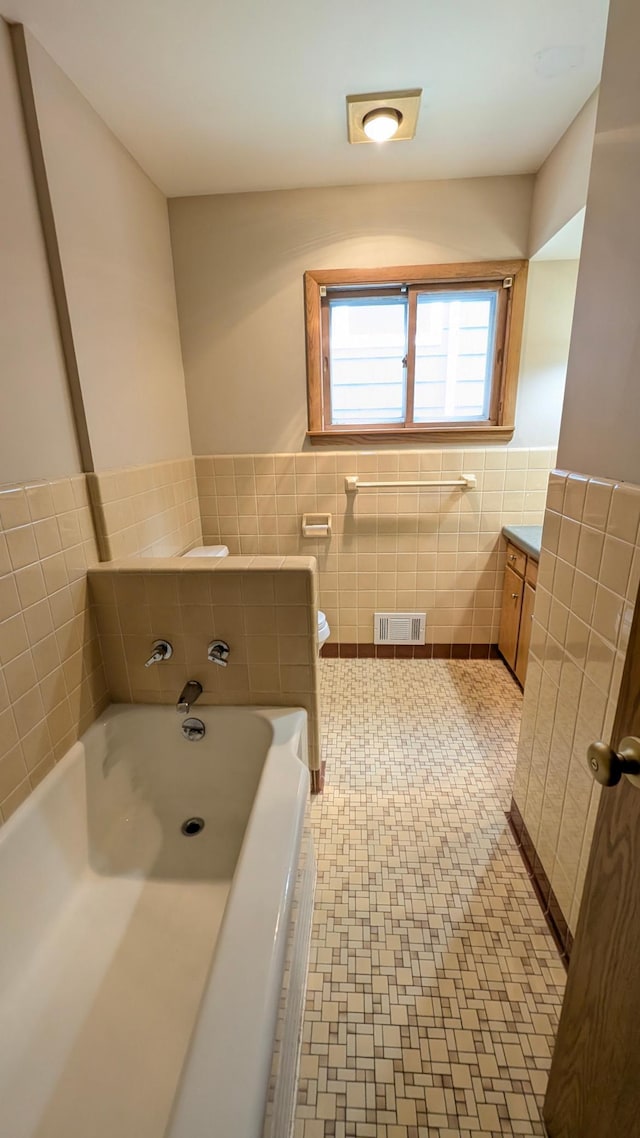 4825 Drew Ave S, Minneapolis, MN 55410 - bathroom with tile walls, a garden tub, a wainscoted wall, vanity, and toilet