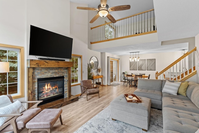 1297 124th Ave NE, Blaine, MN 55434 - living room featuring a high ceiling, wood finished floors, a fireplace, ceiling fan, and stairs