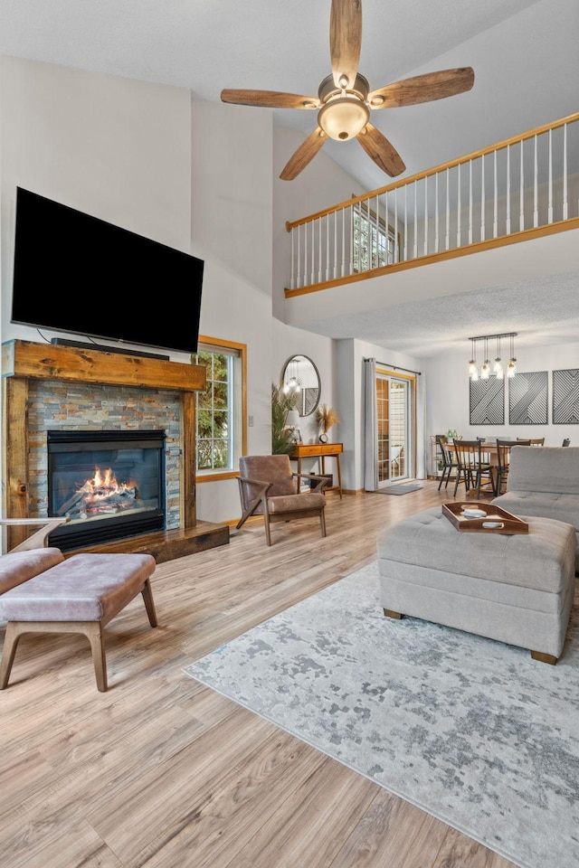 1297 124th Ave NE, Blaine, MN 55434 - living area featuring a towering ceiling, wood finished floors, a stone fireplace, and a ceiling fan