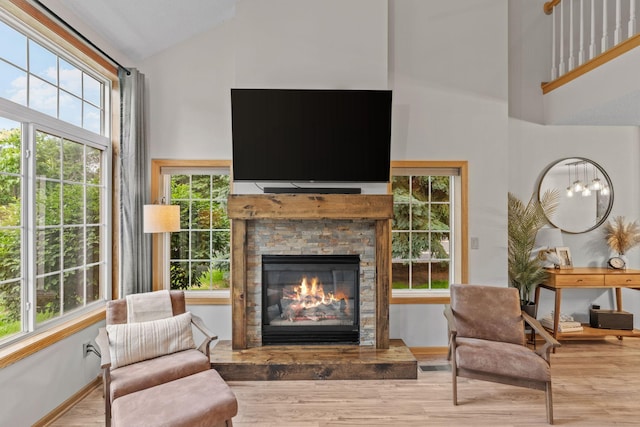 1297 124th Ave NE, Blaine, MN 55434 - living area featuring high vaulted ceiling, healthy amount of natural light, a stone fireplace, and wood finished floors