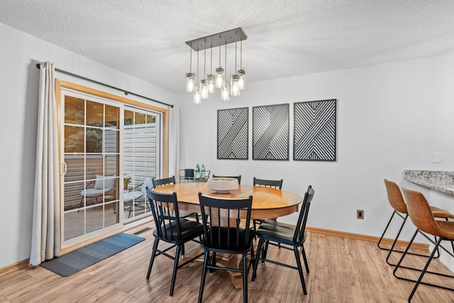 1297 124th Ave NE, Blaine, MN 55434 - dining area with light wood finished floors, a textured ceiling, and a chandelier